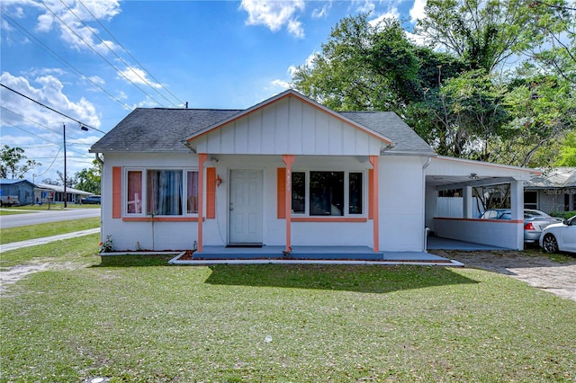 bungalow featuring an attached carport, a shingled roof, and a front lawn