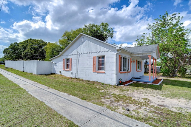 view of property exterior featuring a lawn, concrete block siding, and fence