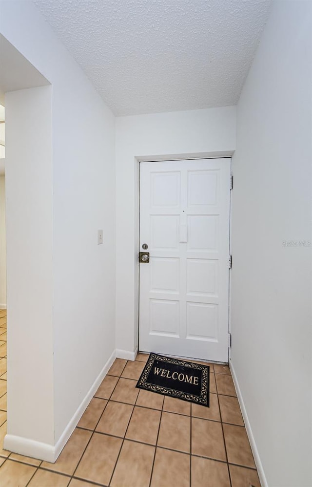 doorway featuring a textured ceiling and light tile patterned floors