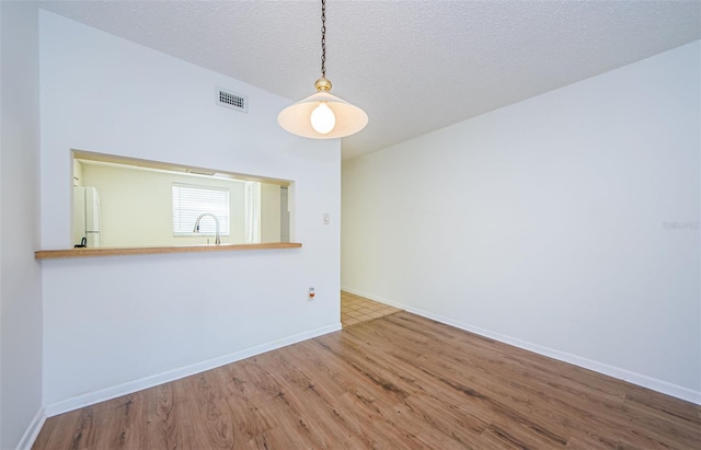 empty room featuring hardwood / wood-style flooring, sink, and a textured ceiling