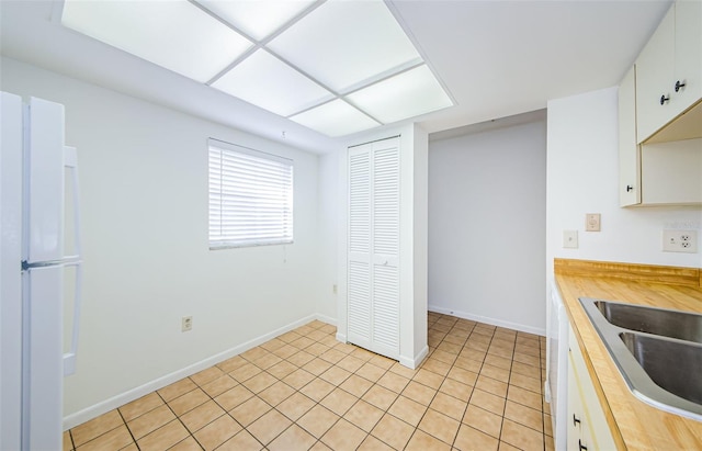 kitchen featuring light tile patterned flooring, sink, and white cabinets