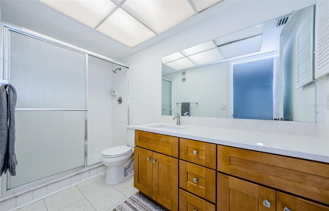 bathroom featuring vanity, toilet, tile patterned floors, and a shower with shower door