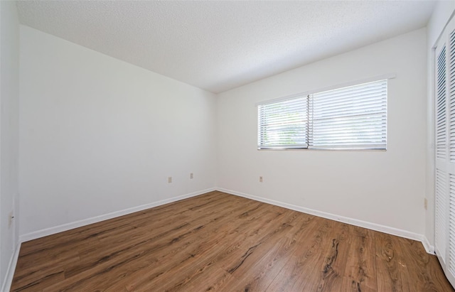 unfurnished room featuring wood-type flooring and a textured ceiling