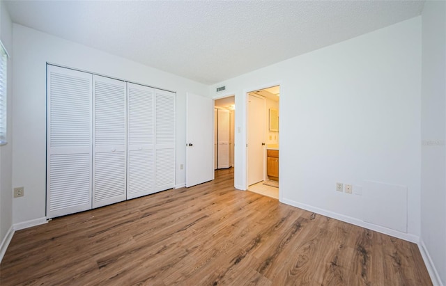 unfurnished bedroom featuring a textured ceiling, light hardwood / wood-style flooring, and a closet