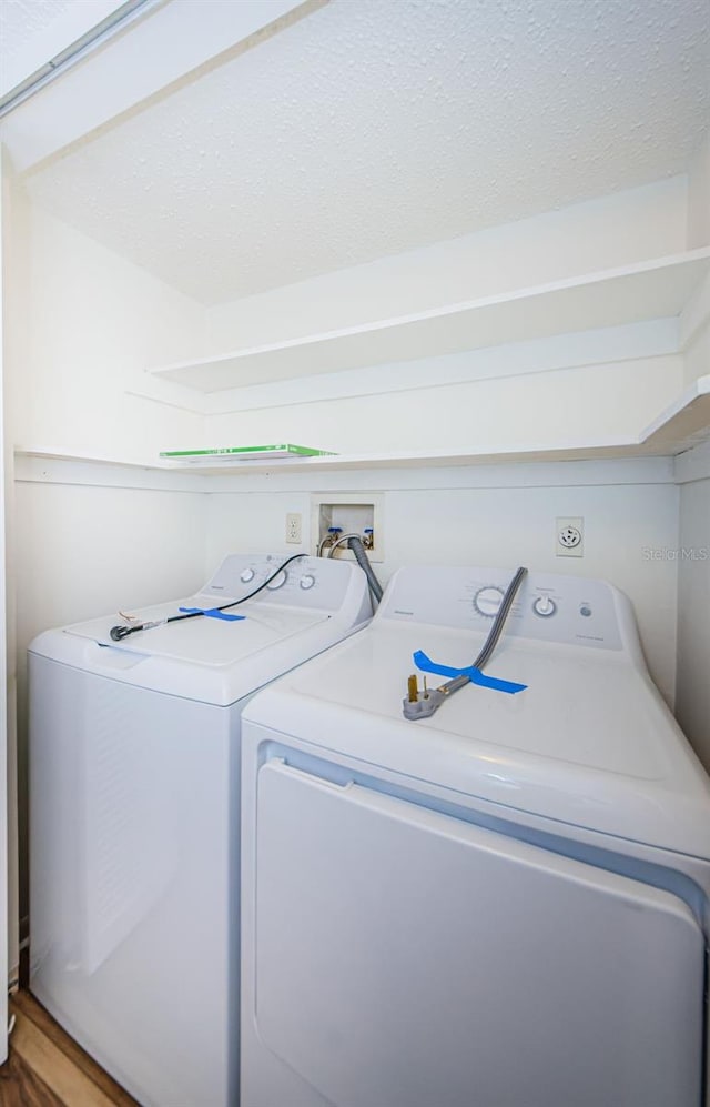 washroom featuring a textured ceiling, hardwood / wood-style flooring, and washing machine and dryer