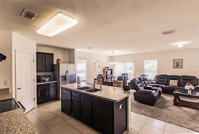 kitchen with a kitchen island with sink, black appliances, sink, a chandelier, and light tile patterned flooring