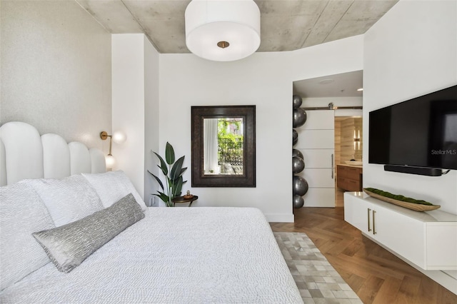 bedroom featuring ensuite bathroom, a barn door, and parquet floors