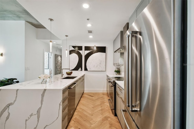 kitchen featuring appliances with stainless steel finishes, light stone countertops, pendant lighting, light parquet floors, and sink