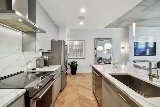 kitchen with appliances with stainless steel finishes, hanging light fixtures, sink, and wall chimney exhaust hood