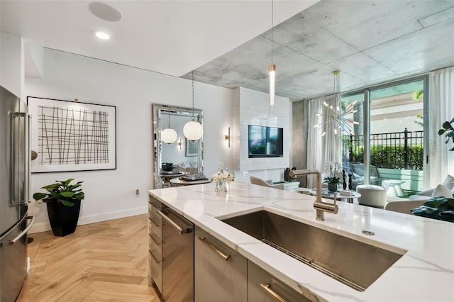 kitchen featuring hanging light fixtures, light stone countertops, sink, and stainless steel appliances