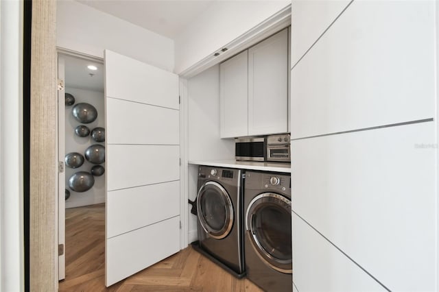 laundry area with cabinets, washing machine and clothes dryer, and light parquet flooring