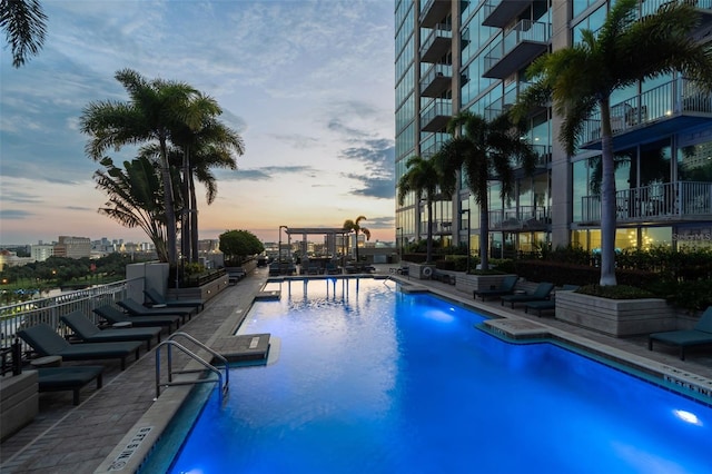 pool at dusk with a patio area