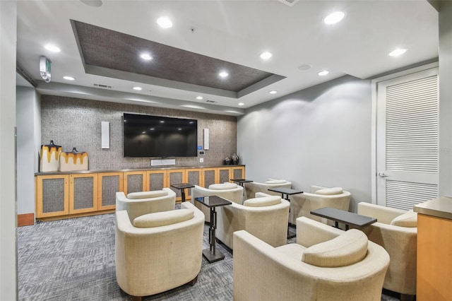 carpeted cinema room with a raised ceiling