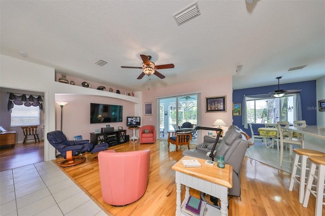 living room with a textured ceiling, light hardwood / wood-style floors, and ceiling fan