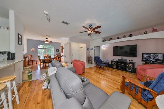 living room with ceiling fan, a textured ceiling, and light hardwood / wood-style floors