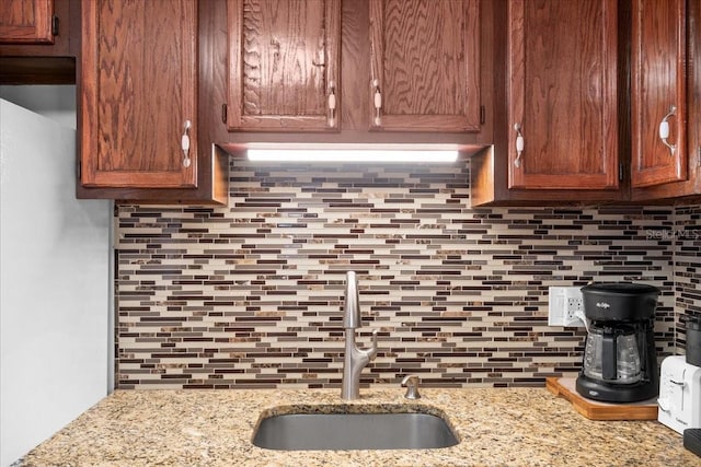 kitchen featuring light stone counters, tasteful backsplash, and sink