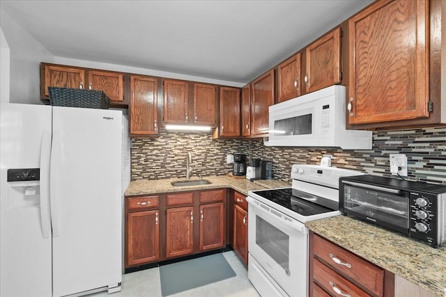 kitchen with light stone counters, backsplash, sink, and white appliances