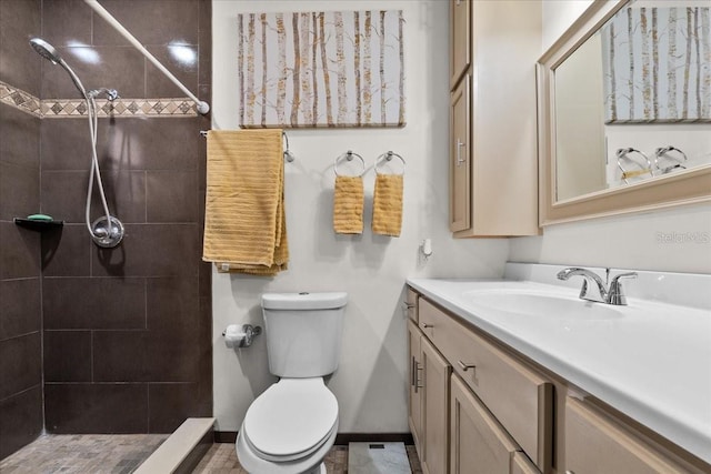 bathroom featuring tile patterned floors, toilet, vanity, and tiled shower