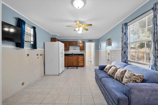 tiled living room featuring ornamental molding, tile walls, ceiling fan, and sink