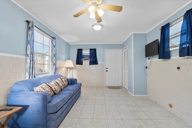 tiled living room featuring ceiling fan, tile walls, and ornamental molding