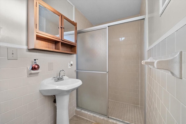 bathroom with tile walls, a shower with shower door, tile patterned flooring, and tasteful backsplash