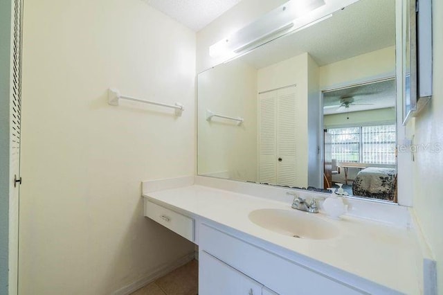 bathroom featuring ceiling fan, vanity, tile patterned flooring, and a textured ceiling