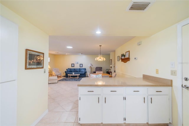 kitchen featuring light tile patterned floors, hanging light fixtures, kitchen peninsula, and white cabinetry