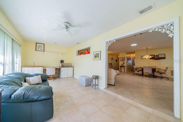 tiled living room featuring ceiling fan and a textured ceiling