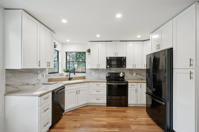 kitchen with black appliances, light hardwood / wood-style floors, and white cabinets