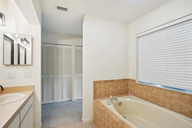 bathroom featuring a relaxing tiled tub, vanity, a textured ceiling, and tile patterned floors