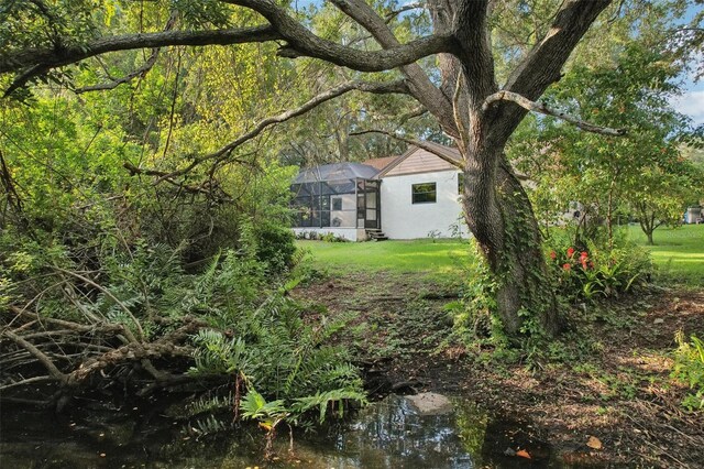 view of yard with a water view and glass enclosure