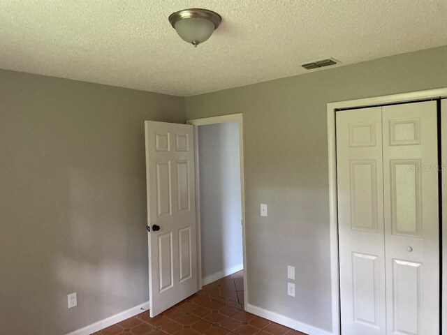 8602 Stoner Rd, Riverview, FL 33569 - unfurnished bedroom featuring a closet, dark tile patterned flooring, a textured ceiling, visible vents, and baseboards