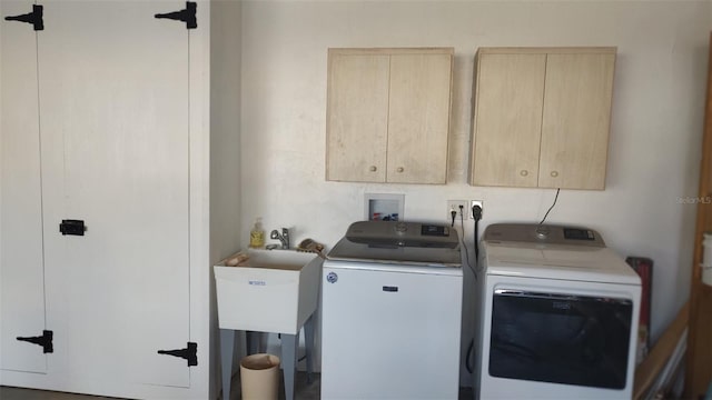 clothes washing area with washer and clothes dryer, sink, and cabinets