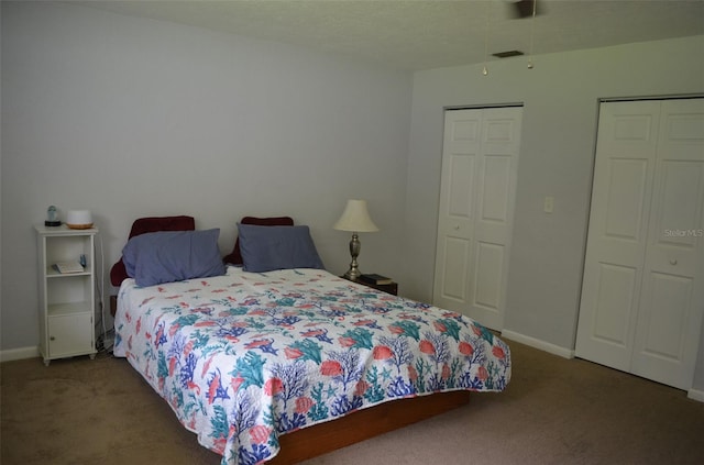 bedroom featuring dark carpet and two closets