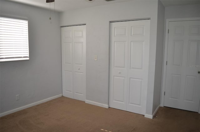 unfurnished bedroom with carpet floors and two closets