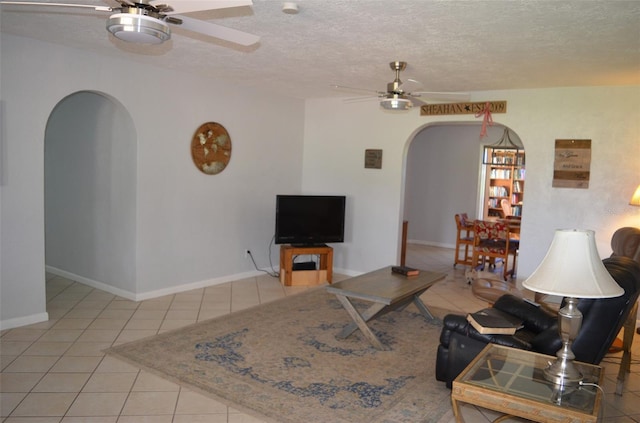 tiled living room with ceiling fan and a textured ceiling