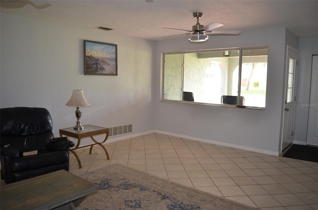 sitting room featuring ceiling fan, light tile patterned flooring, and a textured ceiling