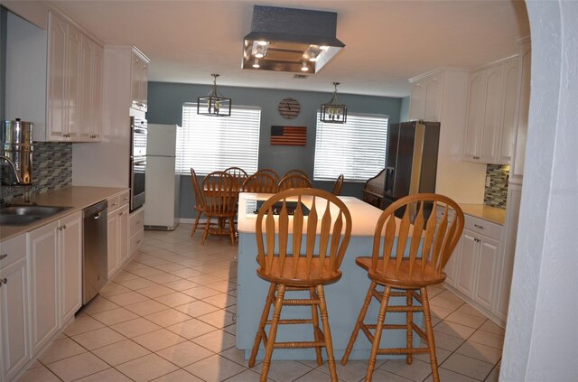 kitchen featuring pendant lighting, sink, white cabinetry, decorative backsplash, and appliances with stainless steel finishes