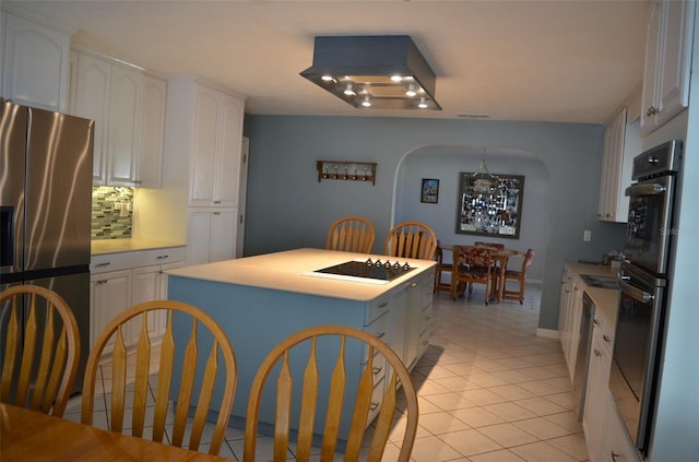 kitchen featuring decorative backsplash, white cabinets, appliances with stainless steel finishes, and light tile patterned floors