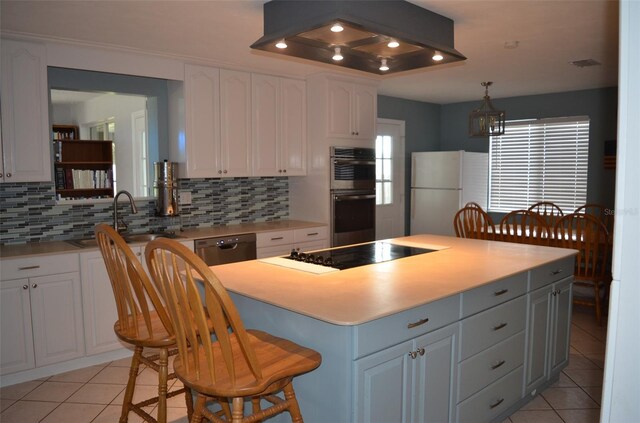 kitchen featuring hanging light fixtures, a kitchen island, white cabinetry, appliances with stainless steel finishes, and decorative backsplash