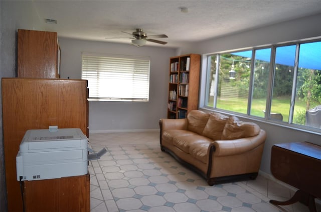 living room with a textured ceiling and ceiling fan