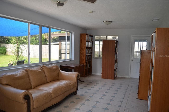 living room featuring a textured ceiling, ceiling fan, and plenty of natural light