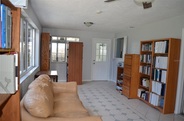 tiled living room with a textured ceiling and ceiling fan