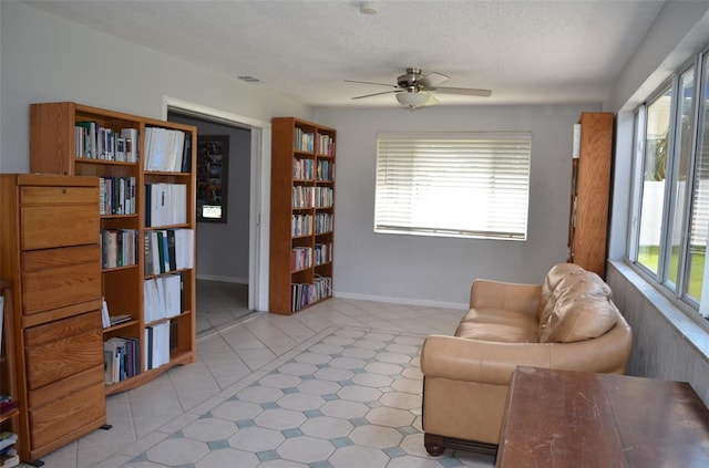 sitting room featuring ceiling fan, light tile patterned floors, and a textured ceiling