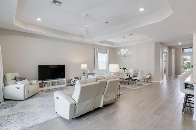 living room with light hardwood / wood-style floors, a tray ceiling, and plenty of natural light