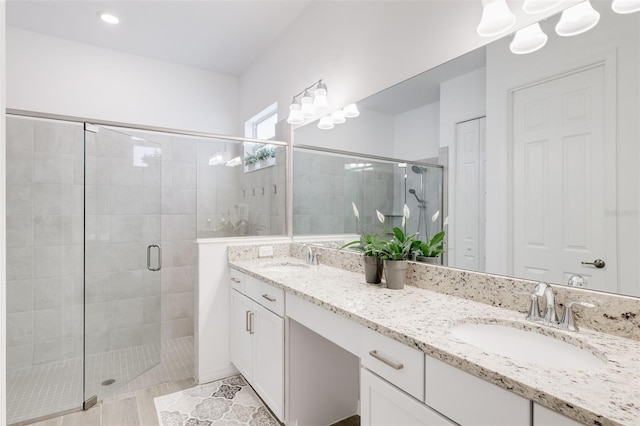 bathroom featuring a shower with shower door and vanity