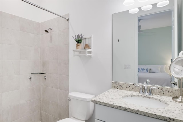 bathroom featuring a tile shower, vanity, and toilet