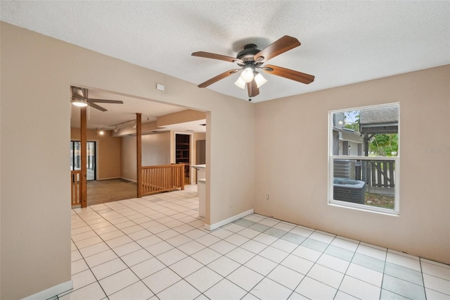 empty room featuring ceiling fan, light tile patterned flooring, and a textured ceiling