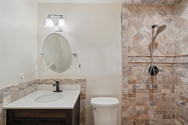 bathroom featuring a tile shower, vanity, and toilet