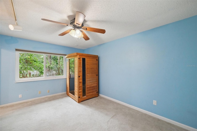 unfurnished bedroom featuring a textured ceiling, ceiling fan, and light carpet